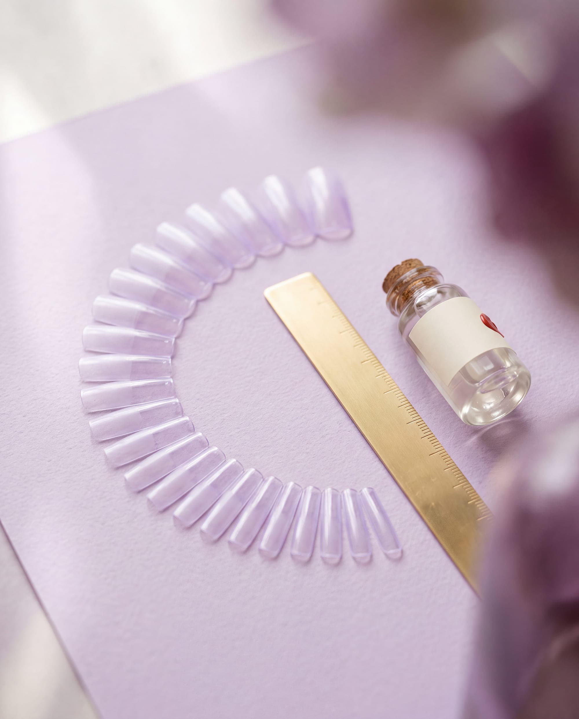 An arc of clear press-on sizing tips beside a brass ruler
